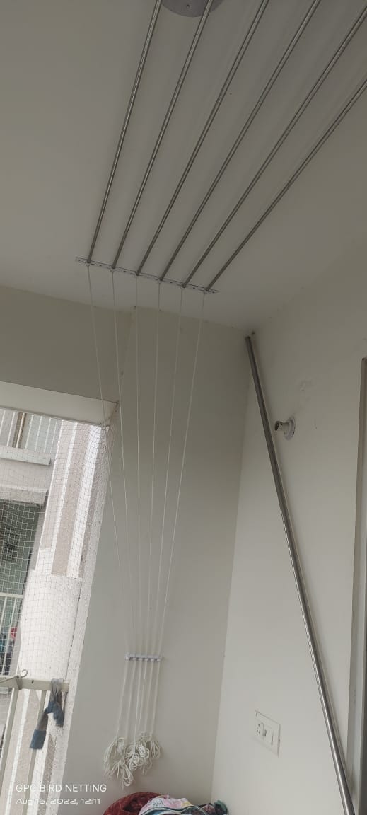 Pulley-operated cloth drying rack with clothes hanging in a bright utility area